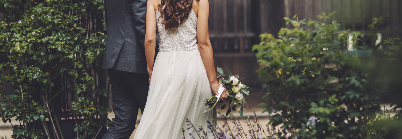 A couple in wedding attire beside a garden gate